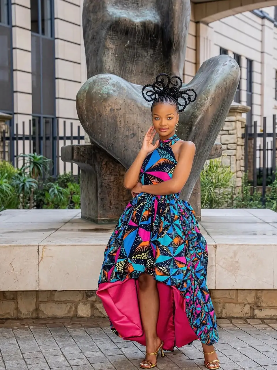 Halter-neck print dress with a high-low skirt beside a bronze sculpture